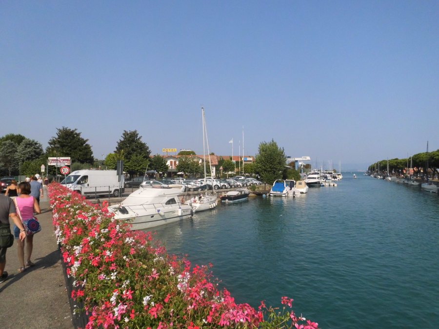 Blumen gesäumte Uferpromenade mit Booten am Gardasee